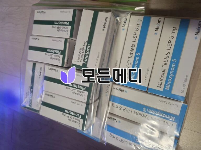Stack of medicine boxes with green and blue bands, labeled Finasteride and Minoxidil, arranged in a container.