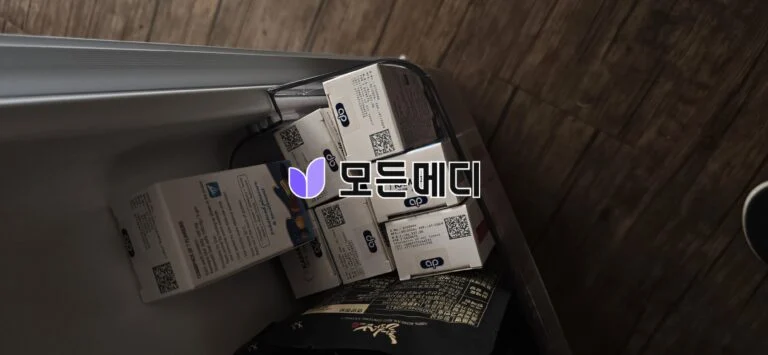 Freezer drawer with stacked white boxes labeled CP and QR codes, on a wooden floor, seen from above/side angle