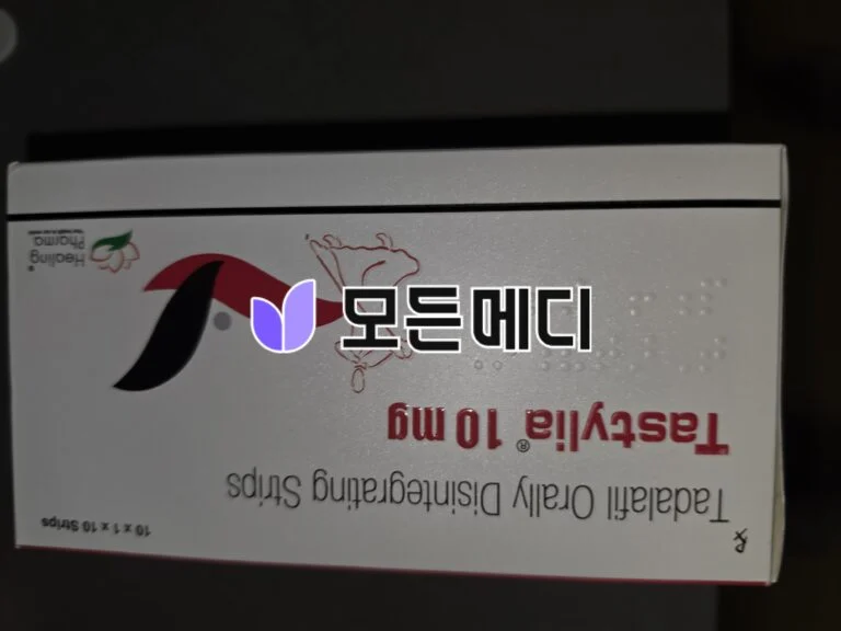 Upside-down close-up of a white product box with a purple leaf logo and red Korean text visible along the edge of the box.