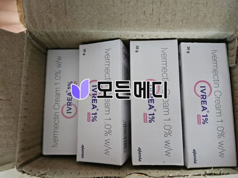 Several white boxes with pink circular branding and purple leaf-like logo stacked inside a brown cardboard shipping box, seen from above