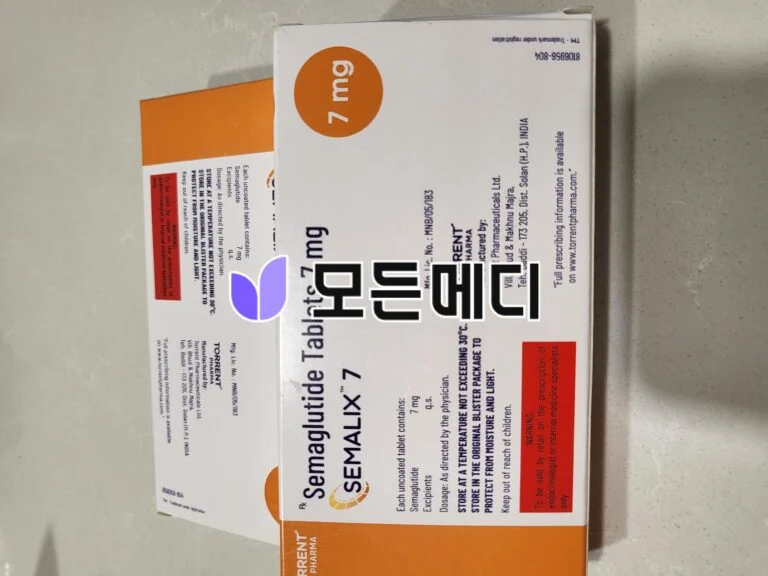 White and orange medicine box with an orange circular logo; text and warnings visible on the sides (rotated orientation).