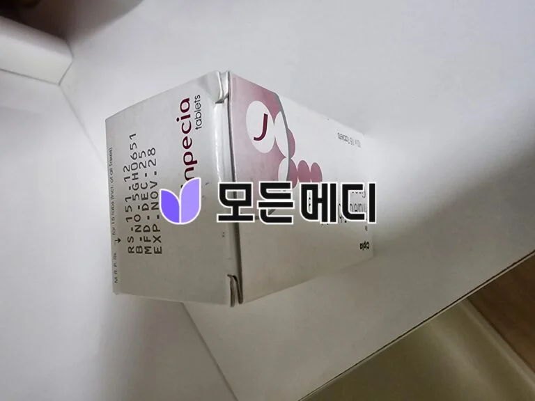 Cardboard packaging box resting on a white surface, showing a purple graphic on the side.