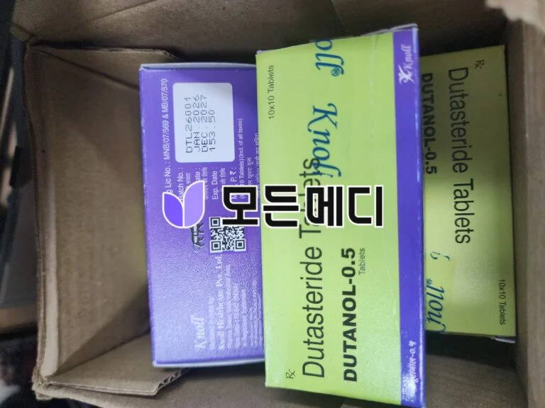 Purple and lime green boxes of dutasteride tablets inside a cardboard shipping box, partially visible.